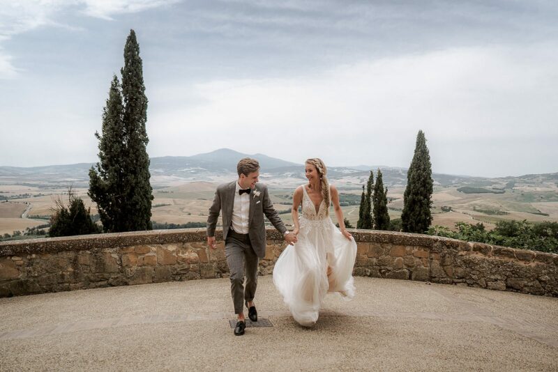 Bride and groom running together while holding hands during their grand Italian elopement, shot by Blitzkneisser